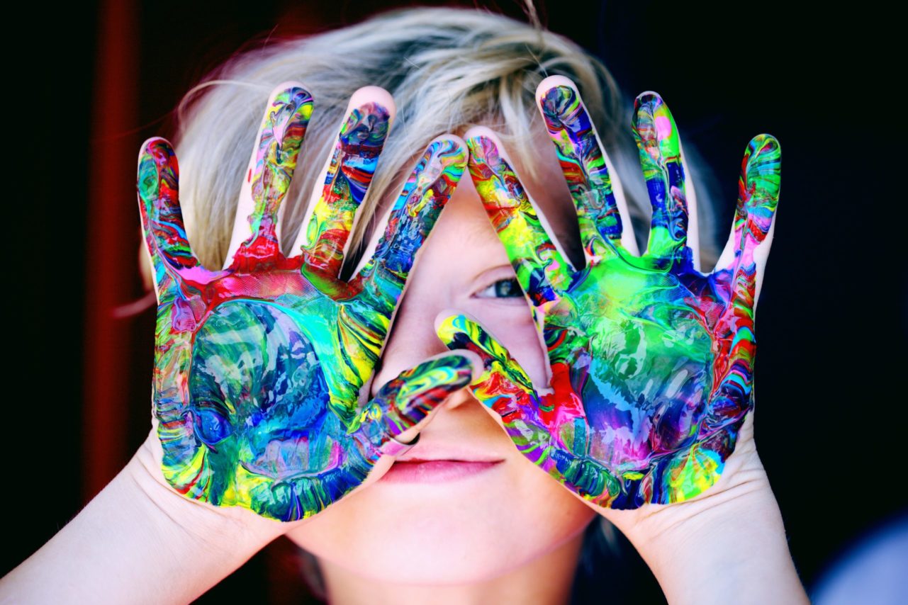 Enfant avec les mains pleines de couleurs, symbole de la pureté et de la joie de vivre. Cette image illustre la joie de vivre et la pureté de l'enfance, et peut être utilisée pour promouvoir des campagnes pour les droits des enfants et leur épanouissement.